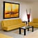 A contemporary studio apartment kitchenette looks out to a living area with 2 sofas, a chair, 2 coffee tables, a telephone, wall art and a decorative floor vase